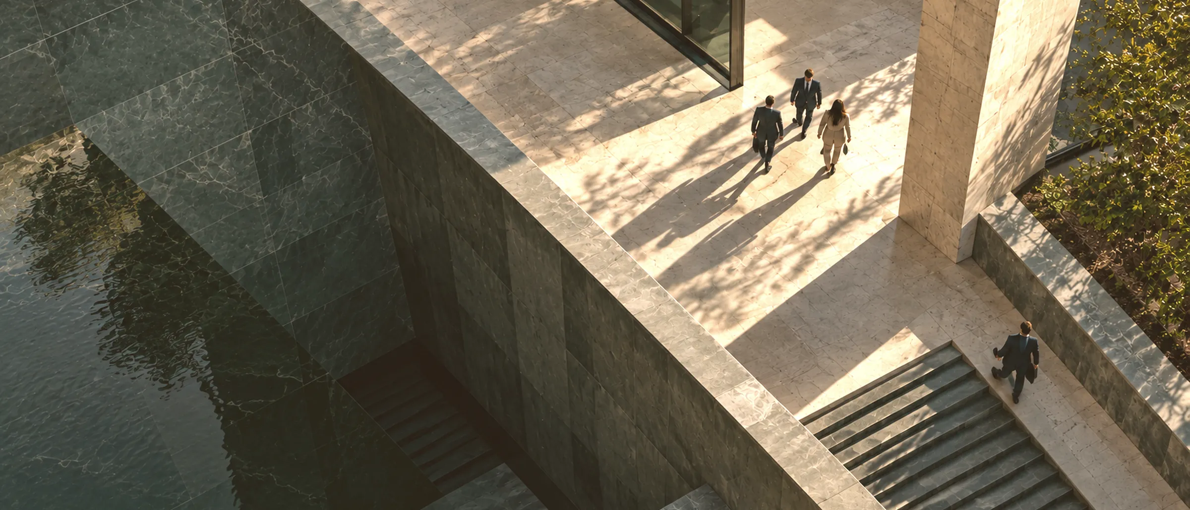 Aerial view of people walking across a sunlit stone terrace and stairs